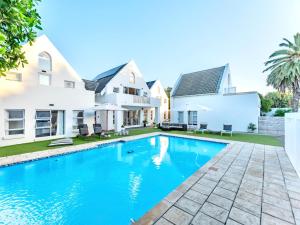 a swimming pool in front of a house at Adrift Guesthouse in St Francis Bay +6 photos