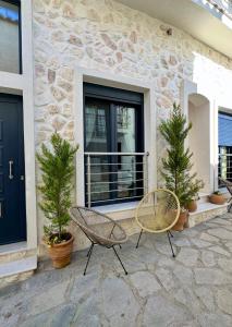 a patio with two chairs and trees in front of a building at Avra Guesthouse in Limenas