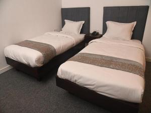 two beds sitting next to each other in a room at Al Aziz Hotel Sylhet in Sylhet
