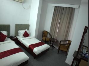 a hotel room with two beds and a table and chairs at Al Aziz Hotel Sylhet in Sylhet +2 photos