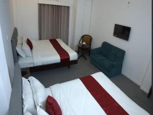 a hotel room with two beds and a blue chair at Al Aziz Hotel Sylhet in Sylhet