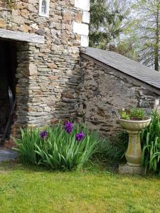 a stone building with flowers and a bird bath at Chambre double dans longère in Soulaines-sur-Aubance