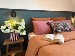 a bed with an open book and a vase of flowers at L'Adresse - Rempart Sud - Eguisheim avec garage privé in Eguisheim