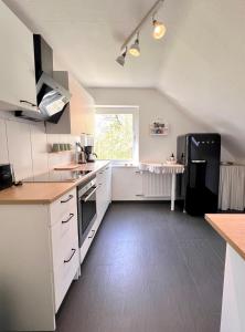 a kitchen with white cabinets and a black refrigerator at Anna's Waldchalet - FeWo Waldblick in Hannoversch Münden