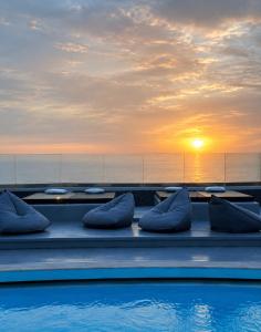 a pool with pillows and a sunset in the background at Abrazo Villas in Imerovigli