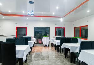 a dining room with white tables and black chairs at Malbon Green Executive Plus Lodge in Kafue