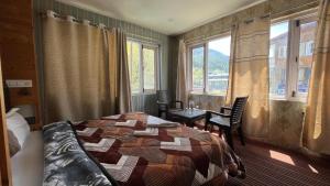 a bedroom with a bed and a table and windows at Hotel Pahalgam Villas in Pahalgām