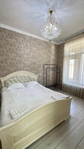 a bedroom with a large white bed with a chandelier at Гостевой дом in Tokmok