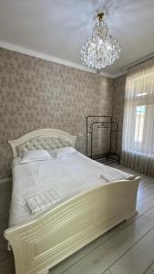 a white bed in a bedroom with a chandelier at Гостевой дом in Tokmok