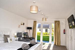 a bedroom with a bed and a couch and a tv at Lytton Tree Lodge Self-Catering Garden Lodges - Near Southwold in Reydon