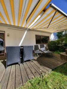 a wooden deck with chairs and an umbrella at Apartment An der Weinstraße in Oberotterbach