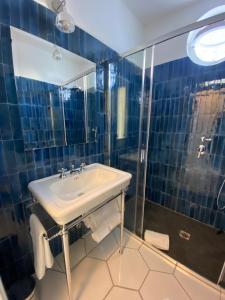 a blue tiled bathroom with a sink and a shower at Casa Stinga in Capri