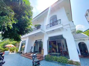 a white house with a balcony and a patio at Thành Đạt Homestay Cát Bà in Cat Ba