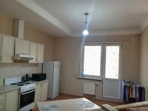 a kitchen with a white refrigerator and a window at Абай2 103 in Astana