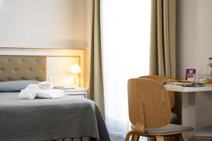 a hotel room with a bed and a table and chair at Hotel Genova Liberty in Genoa