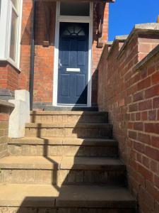 a blue door on a brick house with stairs at Central Kettering Apartment by SJP Ideal for up to 3 Guests in Kettering