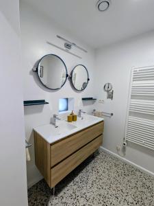 a bathroom with a sink and two mirrors at Aska Logies vakantiewoning in As