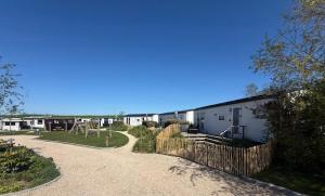 a building with a fence next to a playground at Camping Wad noch Meer in Anna Paulowna