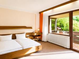 a bedroom with a bed and a desk and a window at BaB Hotels and Apartments-Zum Letzten G'Stehr in Bad Rippoldsau