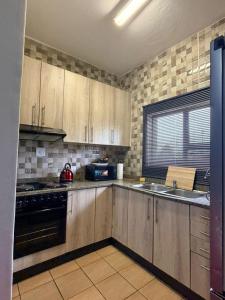 a kitchen with wooden cabinets and a sink and a stove at The Well Apartments in Mbabane