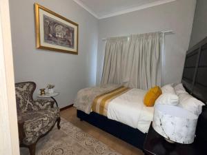 a small bedroom with a bed and a chair at The Well Apartments in Mbabane