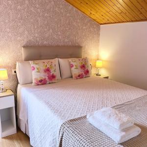 a bedroom with a white bed with pink flowers at Teresa Caeiro in Oia