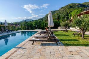 a row of lounge chairs with an umbrella next to a pool at Marcora Historic Mansion in Strongylí