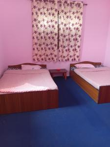 a room with two beds and a window with curtains at Saura place Homestay in Nagarkot +1 photo