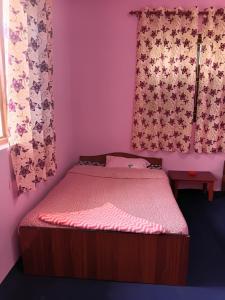 a bed in a room with pink walls and curtains at Saura place Homestay in Nagarkot