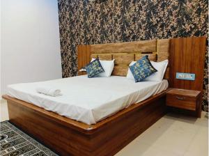 a bedroom with a bed with a wooden headboard and pillows at Hotel Grand Radhe Krishna inn in Vrindāvan
