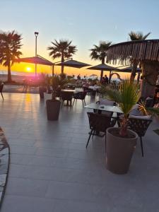 an outdoor patio with tables and chairs and palm trees at A&A Apartments in Golem