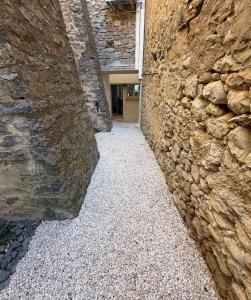 an alley with a stone wall and a building at Les remparts de Sasha in Lapalme