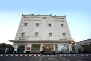 a white building on the corner of a street at شقق اللؤلؤة الذهبي - Golden Pearl Apartments in Sīdī Ḩamzah