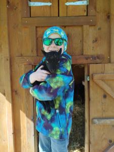 a young boy in sunglasses holding a black cat at Hintererhof in Hintersee