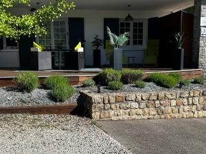 a house with a stone retaining wall and plants at Chambre d'hôtes de la Riaille 400 m de la dolce via in Le Cheylard +3 photos