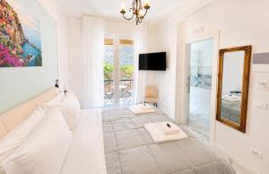 a white bedroom with a large bed and a mirror at Vertigini Suites, Il Rifugio dell Amore per SOLE COPPIE , A 50m dalla Stazione e dalla Via dell Amore con Vista Mare e Intimità Appagante in Riomaggiore