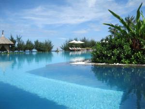 a resort swimming pool with blue water and trees at Muine Bay Resort in Mui Ne