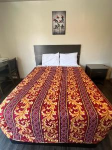 a bed in a room with a colorful blanket on it at World Motel in Lynwood +2 photos