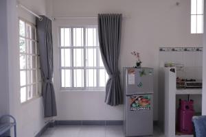 a kitchen with a refrigerator and two windows at Xuan Luom Guesthouse in Phan Thiet
