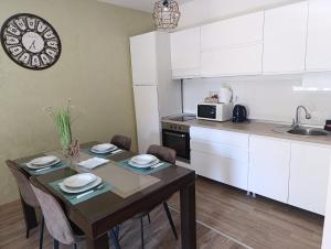 a kitchen with a table with chairs and a clock on the wall at Apartman SATO in Brčko
