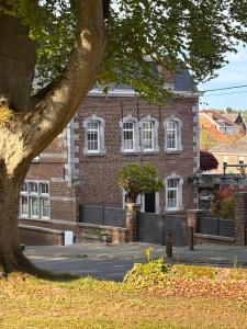 a large brick building with white windows and a tree at La Porte Noire in Courcelles