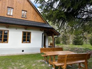 a picnic table and benches in front of a house at Chalupa Vlachovice in Vlachovice