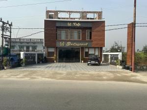 a building with a car parked in front of it at Hotel M Sarthak Dehradun in Dehradun