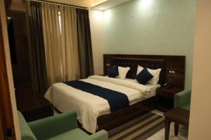 a bedroom with a bed with blue and white pillows at Hotel M Sarthak Dehradun in Dehradun