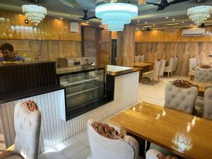 a restaurant with tables and chairs and a man in the background at Hotel M Sarthak Dehradun in Dehradun +20 photos