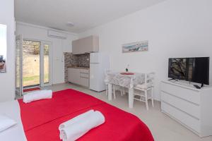 a white room with a red bed and a television at Apartments Luka in Pag