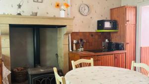 a kitchen with a table and a fireplace with a television at La Maison du Rosier in Saint-Honoré-les-Bains