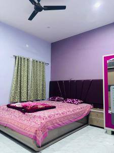 a bedroom with a bed with a purple wall at Ashirwad Niwas in Bokāro