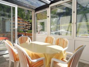 a white table and chairs in a room with windows at Apartment Theresli First Floor in Saas-Almagell