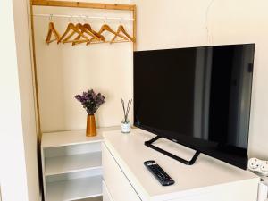 a flat screen tv sitting on top of a white cabinet at Santander suites and rooms atlántico in Santander +23 photos